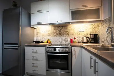 a kitchen with white cabinets and a stainless steel refrigerator at Real Central New Flat - 1' to Metro - Direct Acropolis,Pireus - Best heating and cooling system in Athens