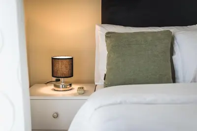 a bed with a green pillow and a lamp on a night stand at Heart of the City in Athens