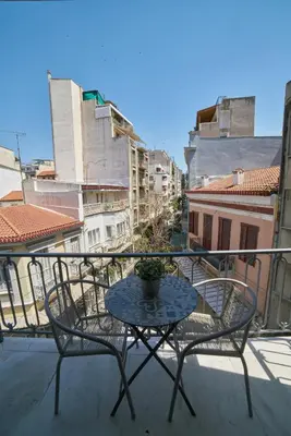 a table and chairs on a balcony with buildings at V&V Central & Elegant Apartment in Athens