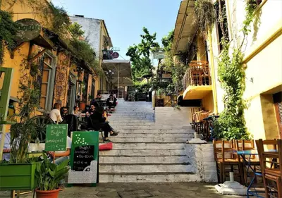 a group of people sitting on the stairs of a street at Acropolis foothill in Athens