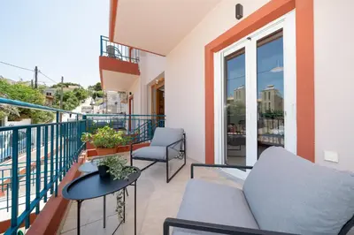 a balcony with a couch and a table and chairs at A&D Apartments in Porto Rafti