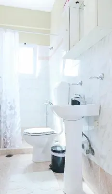 a white bathroom with a toilet and a sink at A&D Apartments in Porto Rafti