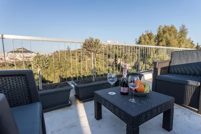 a patio with a table with two glasses of wine at Iris apartment acropolis terrace view in Athens