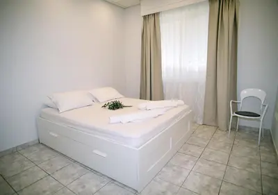 a white bedroom with a white bed and a chair at Best of Athens Apartment in Athens