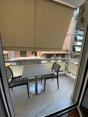 a table and two chairs on a balcony with a window at Stylish Urban Apartment by YHA in Athens