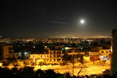 a view of a city at night with the moon at Penthouse with Sea View in Athens