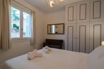 a bedroom with a white bed with a window and a chair at Acro&Polis in Athens