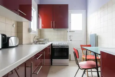 a kitchen with red cabinets and a table with chairs at Athens Vintage Apartment - Ilisia in Athens