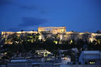 a building on top of a mountain at night at Flat in Monastiraki with stunning view of Acropolis in Athens