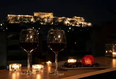 a table with two glasses of wine and a plate of fruit at Mosaics Astonishing Acropolis view Aprtm in Athens