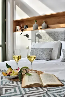 a table with two glasses of wine and a book on a bed at Thission Luxury Homes & SPA by K&K in Athens