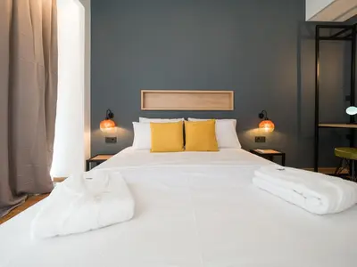 a bedroom with a large white bed with yellow pillows at Luxury Veni Acropolis View Apartment in Athens
