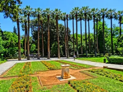 a park with palm trees and a statue in the middle at Luxury Veni Acropolis View Apartment in Athens