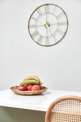 a bowl of fruit on a table with a clock at Athens Premium Suites - Sunny 2 Bedroom Suite with Parking in Athens