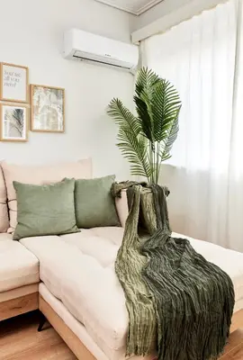 a living room with a couch with a plant on it at Athens Premium Suites - Sunny 2 Bedroom Suite with Parking in Athens