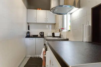 a kitchen with white cabinets and a black counter top at 5* Penthouse Acropoli View Loft in Athens