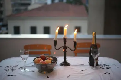 a table with a candle and a bowl of fruit and a bottle of wine at Athenian Vintage Apartments in Athens