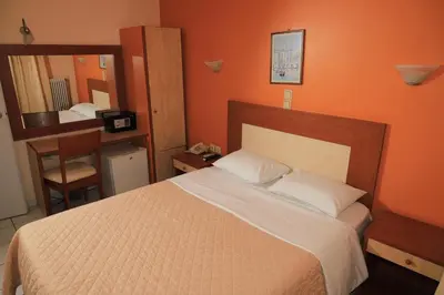 a bedroom with a large bed and a mirror at IKAROS Hotel ELLINIKO in Athens