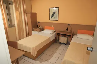 a room with two beds and a desk with a phone at IKAROS Hotel ELLINIKO in Athens