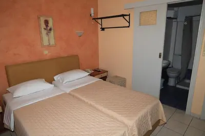 a bedroom with a bed and a bathroom with a toilet at IKAROS Hotel ELLINIKO in Athens