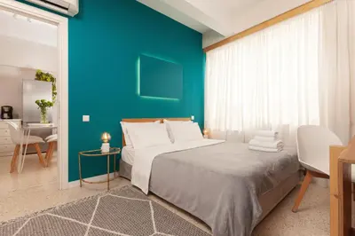 a bedroom with a large bed with a blue wall at The Marble Suites, PLAKA in Athens