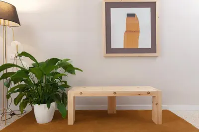 a wooden bench next to a plant and a picture at The Marble Suites, PLAKA in Athens