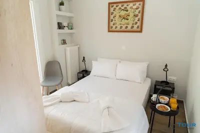 a bedroom with a white bed with a tray of food on a table at Art point under Acropolis in Athens
