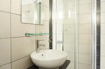 a white bathroom with a sink and a shower at Spacious apartment-600m from the subway in Athens
