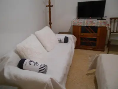 a living room with a white couch and a television at Yiannis Kalimarmaro Studio,Athens Center in Athens