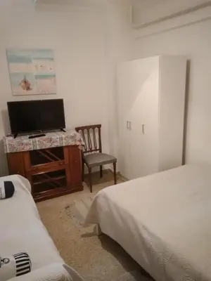 a bedroom with two beds and a tv and a chair at Yiannis Kalimarmaro Studio,Athens Center in Athens