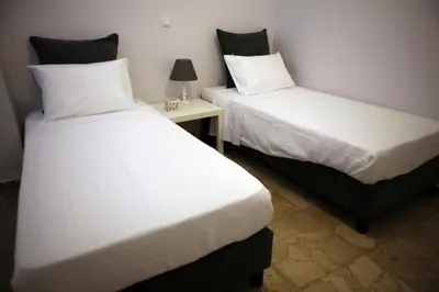 two beds in a room with a table and a bedskirts at Feels like home with luxury details in Athens