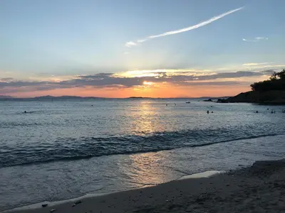 a sunset over a beach with people in the water at Best Seaview Attica in Saronida