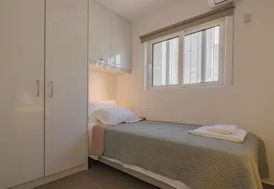 a white bedroom with a bed and a window at Best Seaview Attica in Saronida