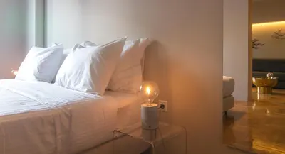 a bed with white pillows and a candle on a glass table at ABA Junior Apartment Veikou street in Athens