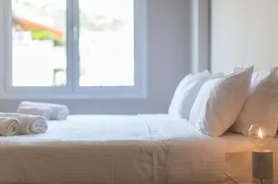 a white bed with white pillows and a window at ABA Junior Apartment Veikou street in Athens