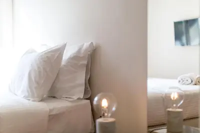 a white bed with white pillows and two candles at ABA Junior Apartment Veikou street in Athens