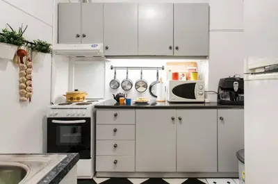 a small kitchen with white cabinets and a microwave at Vintage Charm by the Acropolis! in Athens