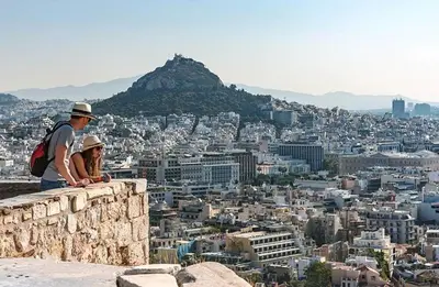 two people sitting on a ledge looking at a city at Vintage Charm by the Acropolis! in Athens