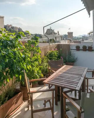 a patio with a wooden table and chairs on a balcony at Ariadne's Penthouse in Central Athens in Athens