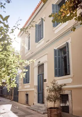 a white house with a blue door on a street at Bohemian Suites Athens - Maison Hotel Adults Only in Athens