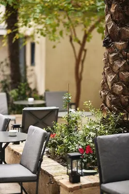 a patio with chairs and tables and flowers at Bohemian Suites Athens - Maison Hotel Adults Only in Athens