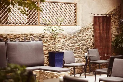 a group of chairs and tables in front of a stone wall at Bohemian Suites Athens - Maison Hotel Adults Only in Athens