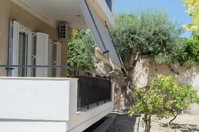 a balcony of a house with a gate and trees at Seaside House in Voula in Athens