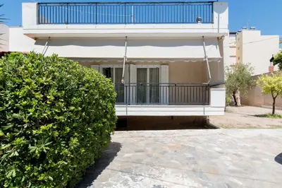 a house with a balcony and a large bush at Seaside House in Voula in Athens