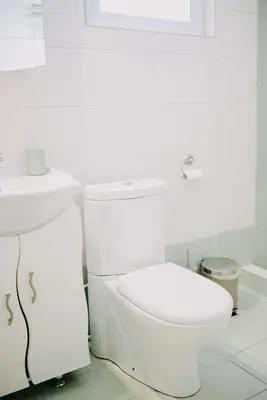 a white bathroom with a toilet and a sink at Best House, Rooftop Aprtm., Marina Zeas Piraeus in Piraeus