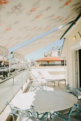 a patio with tables and chairs on a balcony at Best House, Rooftop Aprtm., Marina Zeas Piraeus in Piraeus