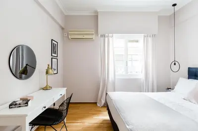 a white bedroom with a bed and a mirror at Acropolis Heart 2BD Apartment in Plaka by UPSTREET in Athens