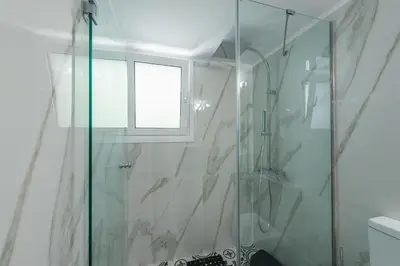 a bathroom with a glass shower with a window at Splash of Glam II 10 Steps from Acropolis in Athens