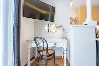 a desk with a chair and a tv on a wall at Splash of Glam II 10 Steps from Acropolis in Athens