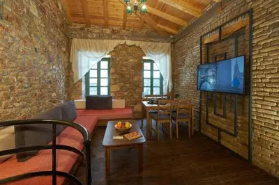 a living room with a couch and a tv on a brick wall at Athenian Residences in Athens